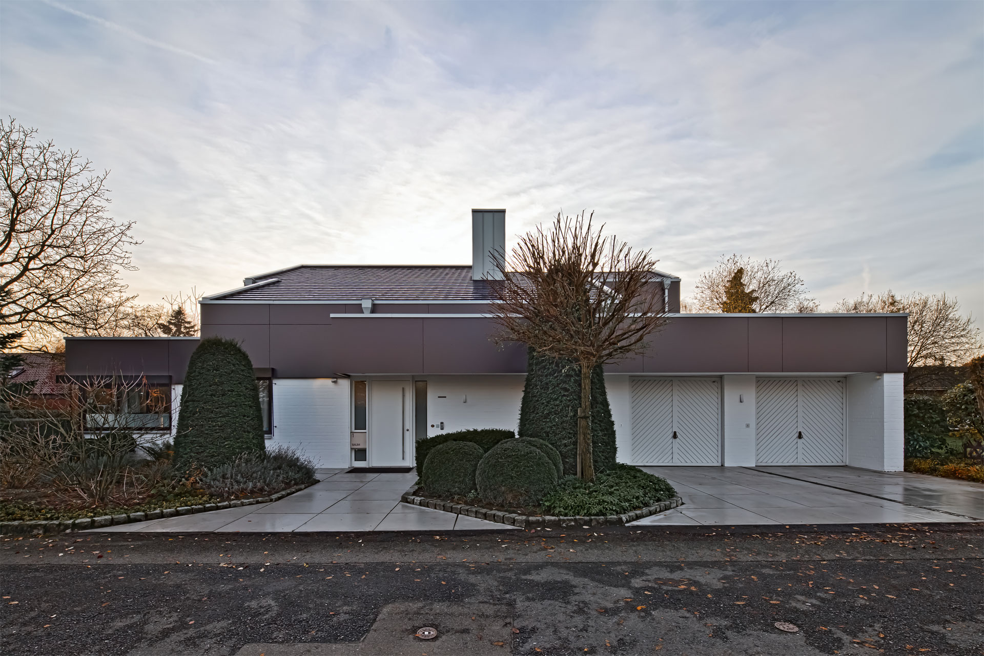 Wohnhaus-Umbau — modernisierte Fassade mit dunkler Verkleidung im Obergeschoss, weißer Sockel, neue Eingangssituation